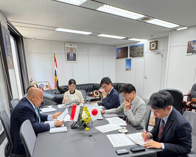 Yemen's Ambassador to Japan Adel al-Sunaini in talks with a JICA official across a meeting table in Tokyo, with Yemeni and Japanese flags on the desk