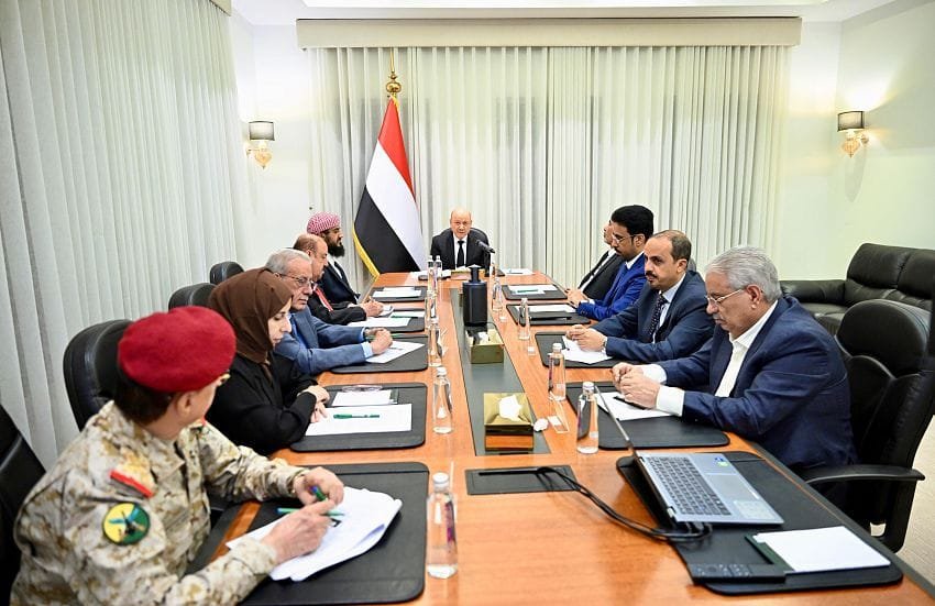 Yemeni officials seated around a conference table beneath the national flag during a government meeting