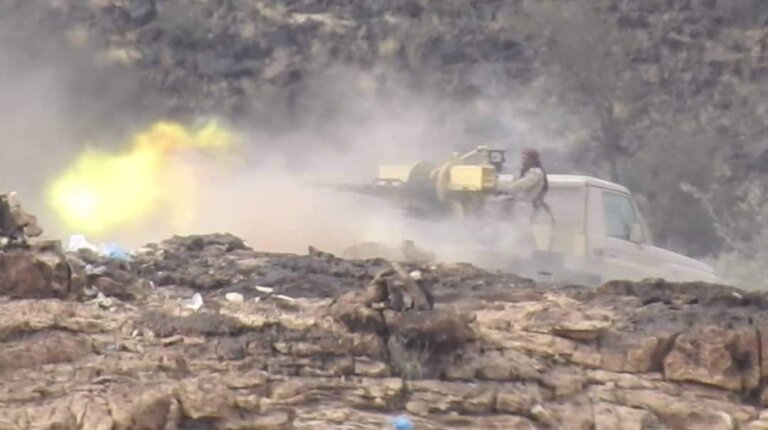 Yemeni government fighters firing a heavy weapon from a pickup truck on a rocky front line in Taiz governorate