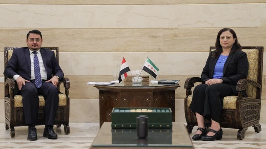 Yemen's chargé d'affaires in Damascus Mohammed Baaker seated with Syrian foreign ministry treaties director Dima Al-Mousa, the Yemeni and Syrian flags on the table between them