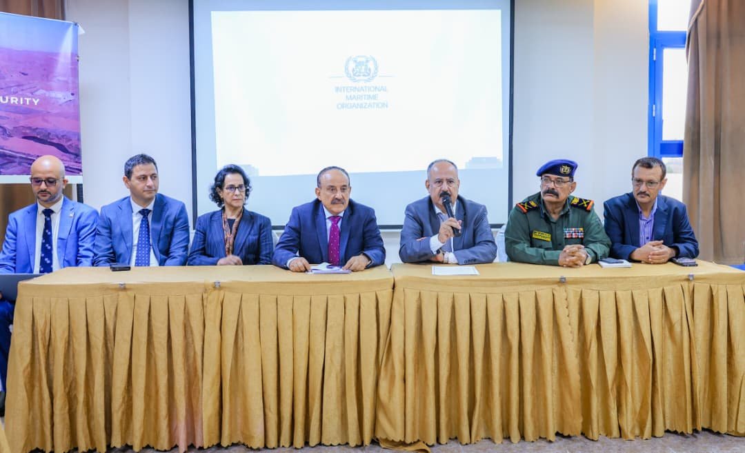 Yemeni Transport Minister Mohsen Haidara al-Omari and officials at the closing session of a maritime security workshop in Aden, with an International Maritime Organization slide displayed behind them