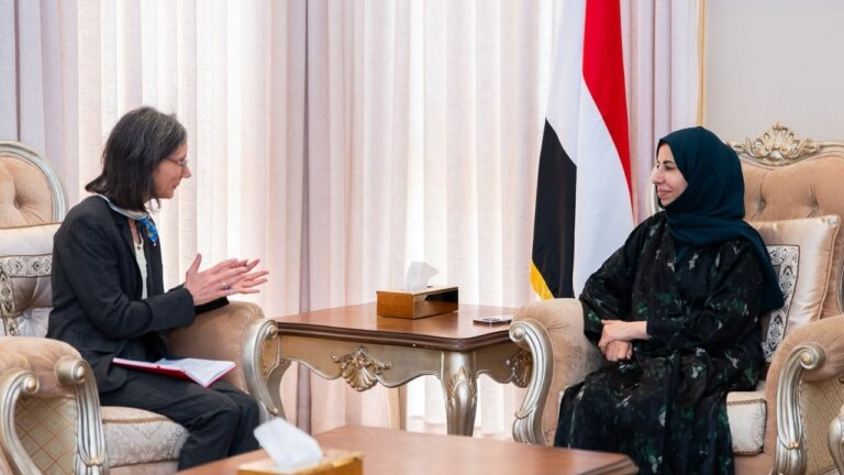 French Ambassador Catherine Corm-Kammoun in conversation with Yemeni Foreign Minister Afrah al-Zouba, the Yemeni flag behind them