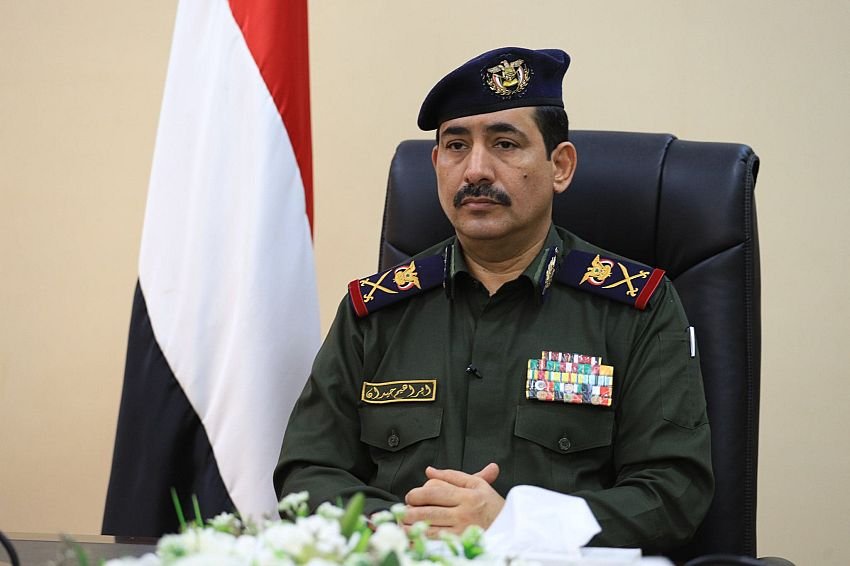 Yemeni Interior Minister Major General Ibrahim Haydan in uniform before the national flag during a video call on security cooperation.