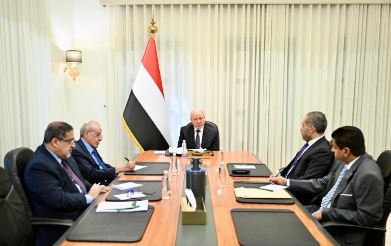 President Rashad al-Alimi chairs a meeting of Yemen's Supreme Committee for Combating Smuggling, seated before the Yemeni flag.