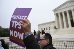 A demonstrator holds a placard reading PROTECT TPS NOW outside a United States courthouse