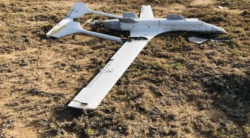 A downed fixed-wing drone lying on open scrubland in Yemen