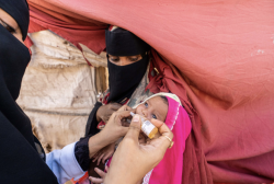A health worker administers oral vaccine drops to a young child in Yemen