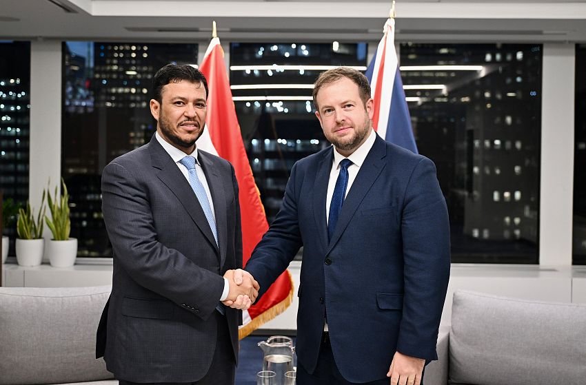 Presidential Leadership Council member Abdullah al-Alimi Bawazir shakes hands with British minister Stephen Doughty in front of Yemeni and British flags in New York