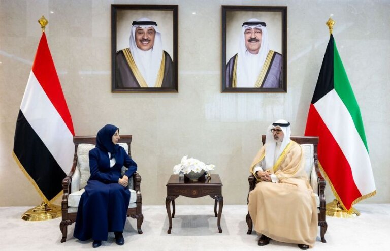 Yemen's foreign minister seated with a Kuwaiti official beneath the Yemeni and Kuwaiti flags