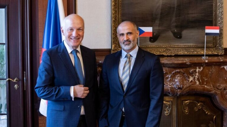 Yemen's ambassador Mohammed al-Hadrami shakes hands with Czech Senator Pavel Fischer beside Czech and Yemeni flags