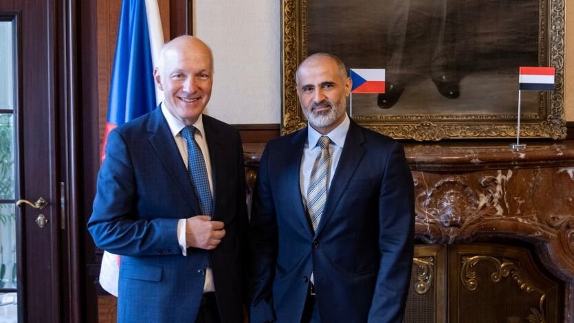 Yemen's ambassador Mohammed al-Hadrami shakes hands with Czech Senator Pavel Fischer beside Czech and Yemeni flags