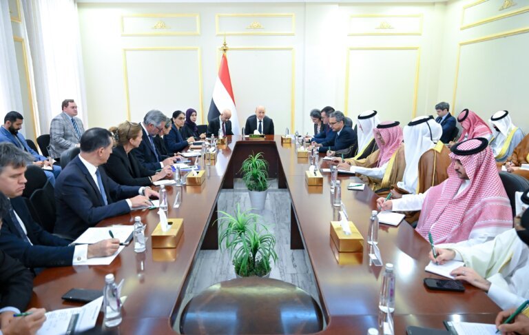 Rashad al-Alimi chairs a meeting under the Yemeni flag with delegations seated along a long table