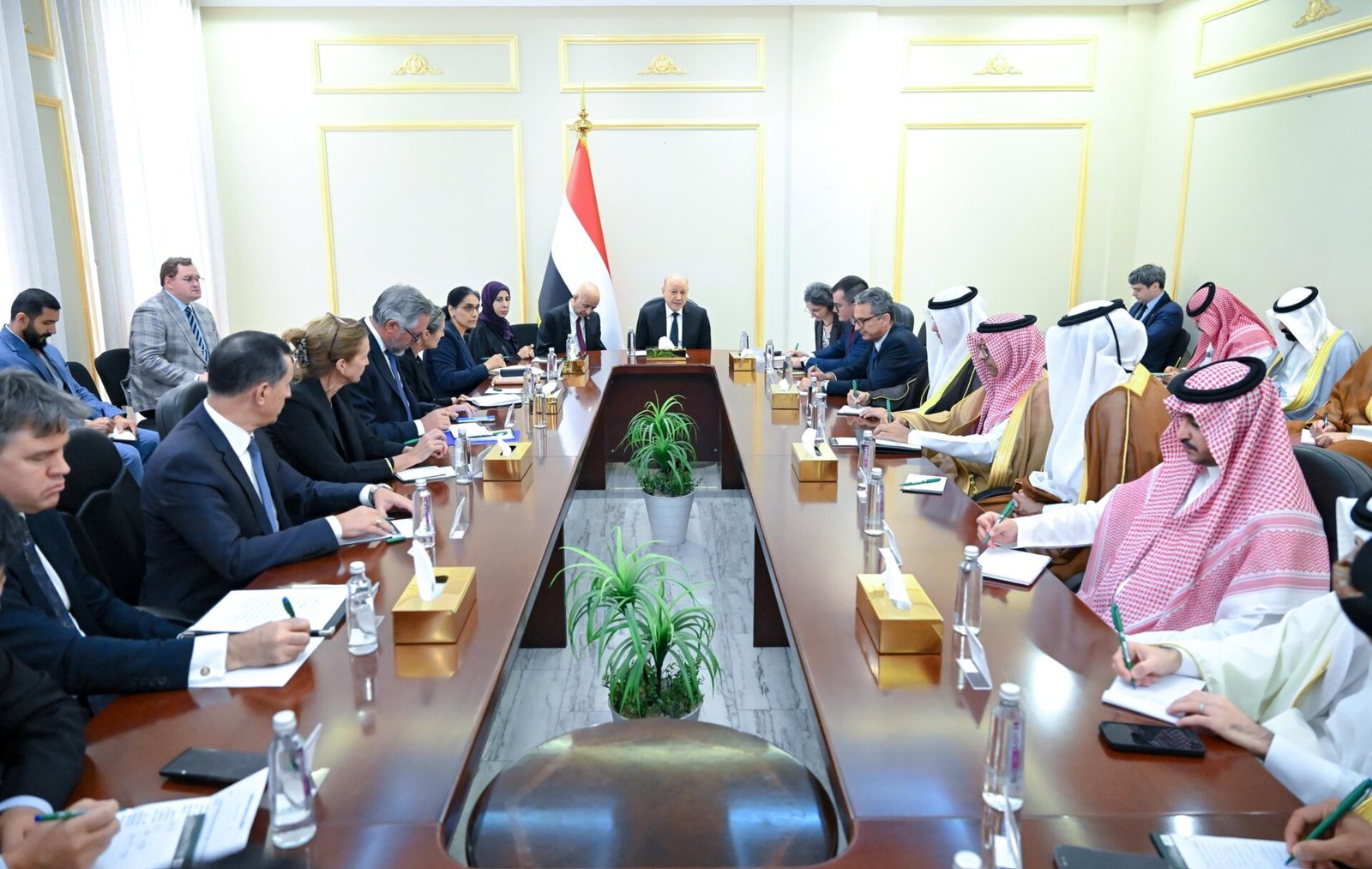 Rashad al-Alimi chairs a meeting under the Yemeni flag with delegations seated along a long table