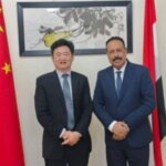 Yemen's minister of public works and roads with the Chinese charge d'affaires in front of the Chinese and Yemeni flags