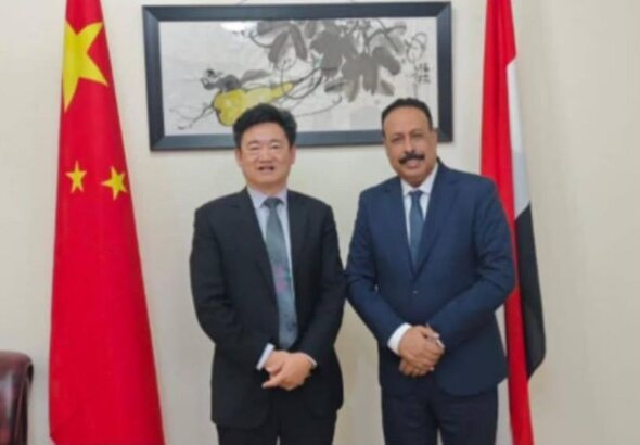 Yemen's minister of public works and roads with the Chinese charge d'affaires in front of the Chinese and Yemeni flags