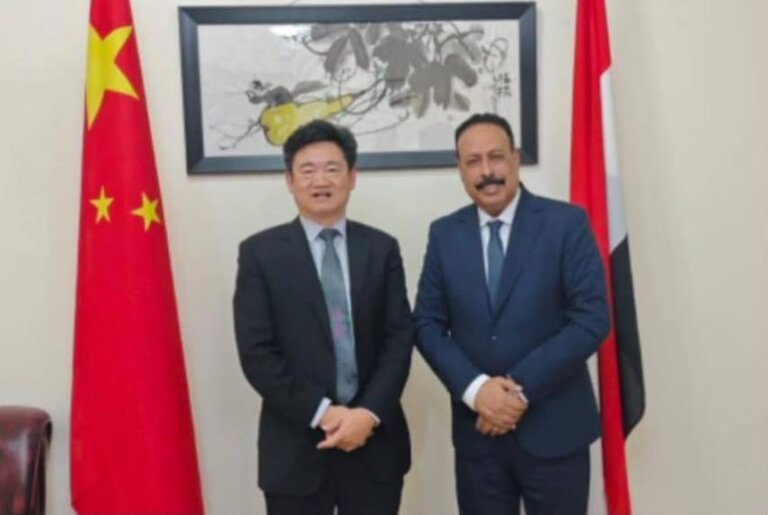 Yemen's minister of public works and roads with the Chinese charge d'affaires in front of the Chinese and Yemeni flags