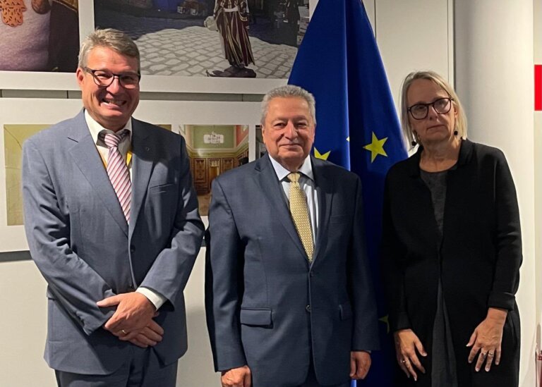 Yemen's ambassador to the European Union, Mohammed Taha Mustafa, stands with two officials in front of a European Union flag in Brussels.