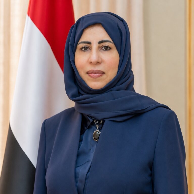 Yemeni Foreign Minister Afrah al-Zouba standing in front of the Yemeni flag
