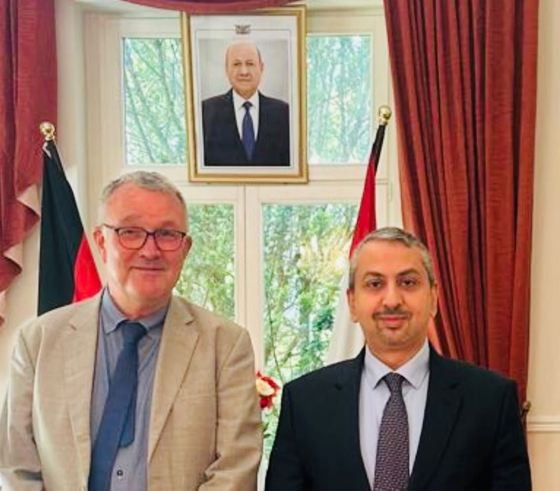 Yemeni ambassador Lou'ay al-Eryani stands with German analyst Michael Lüders beside Yemeni and German flags in Berlin