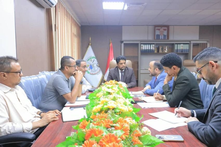 Yemeni officials and UN staff seated around a table during talks on vocational training in Aden
