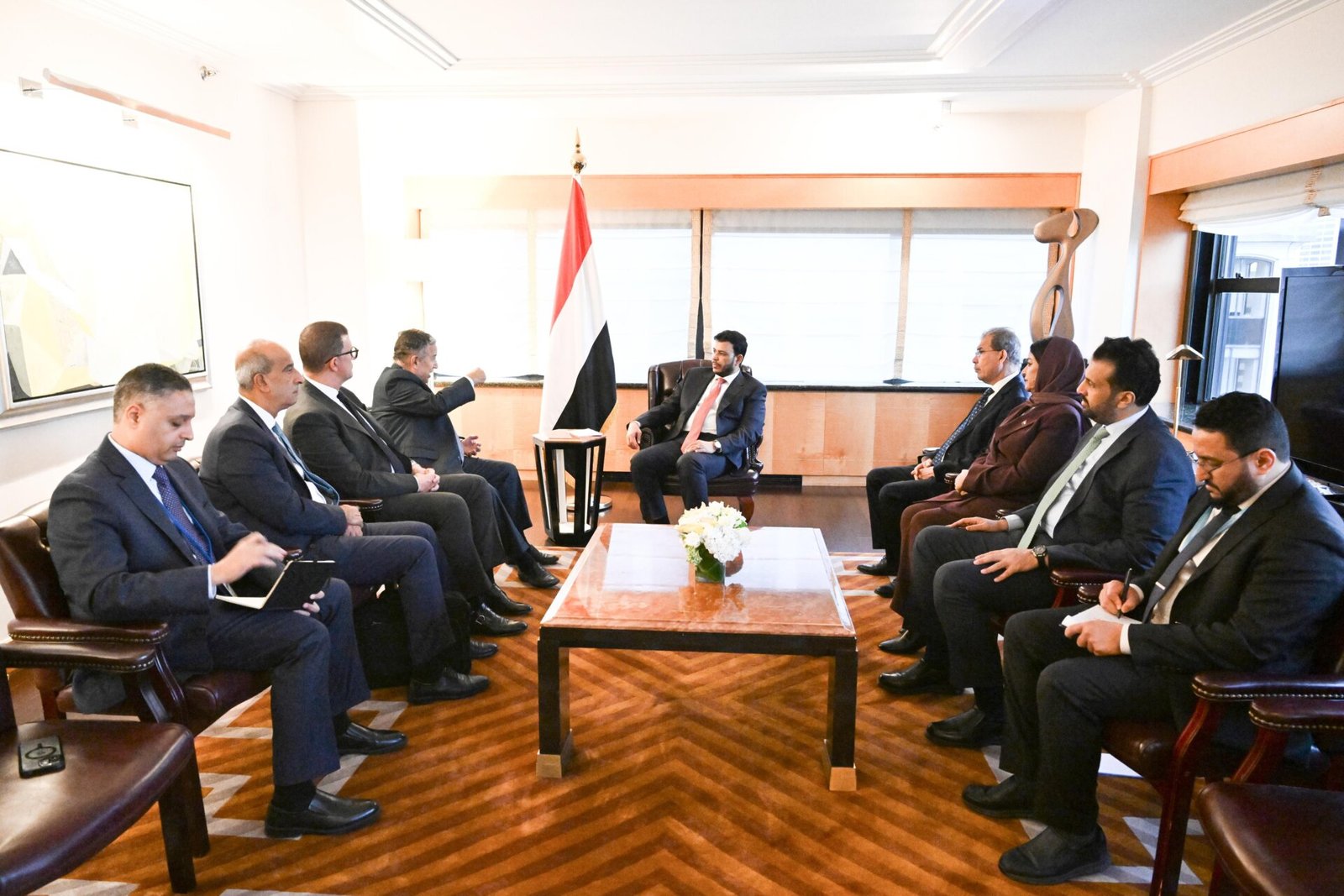 Yemeni and Arab League delegations seated around a table with a Yemeni flag during talks in New York