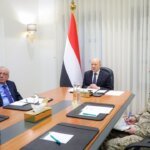 President Rashad al-Alimi chairs a meeting with Yemeni officials and a military commander beside the national flag