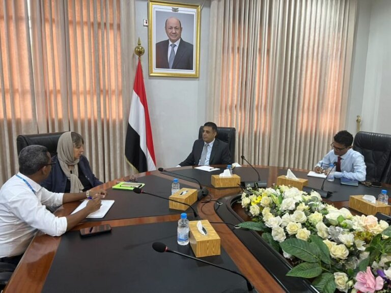 Yemeni State Minister for Displacement and Illegal Migration Waleed al-Abara meeting officials around a conference table beneath the Yemeni flag