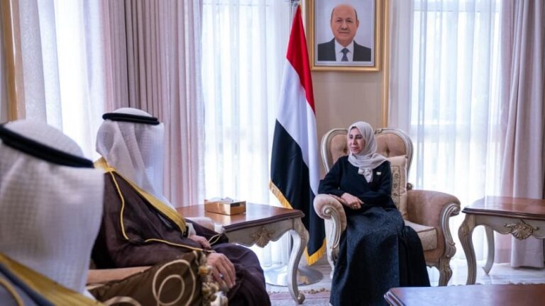 Yemeni Foreign Minister Afrah al-Zouba sits opposite Kuwait’s ambassador Falah al-Mutairi in a reception room with the Yemeni flag and a portrait of Rashad al-Alimi