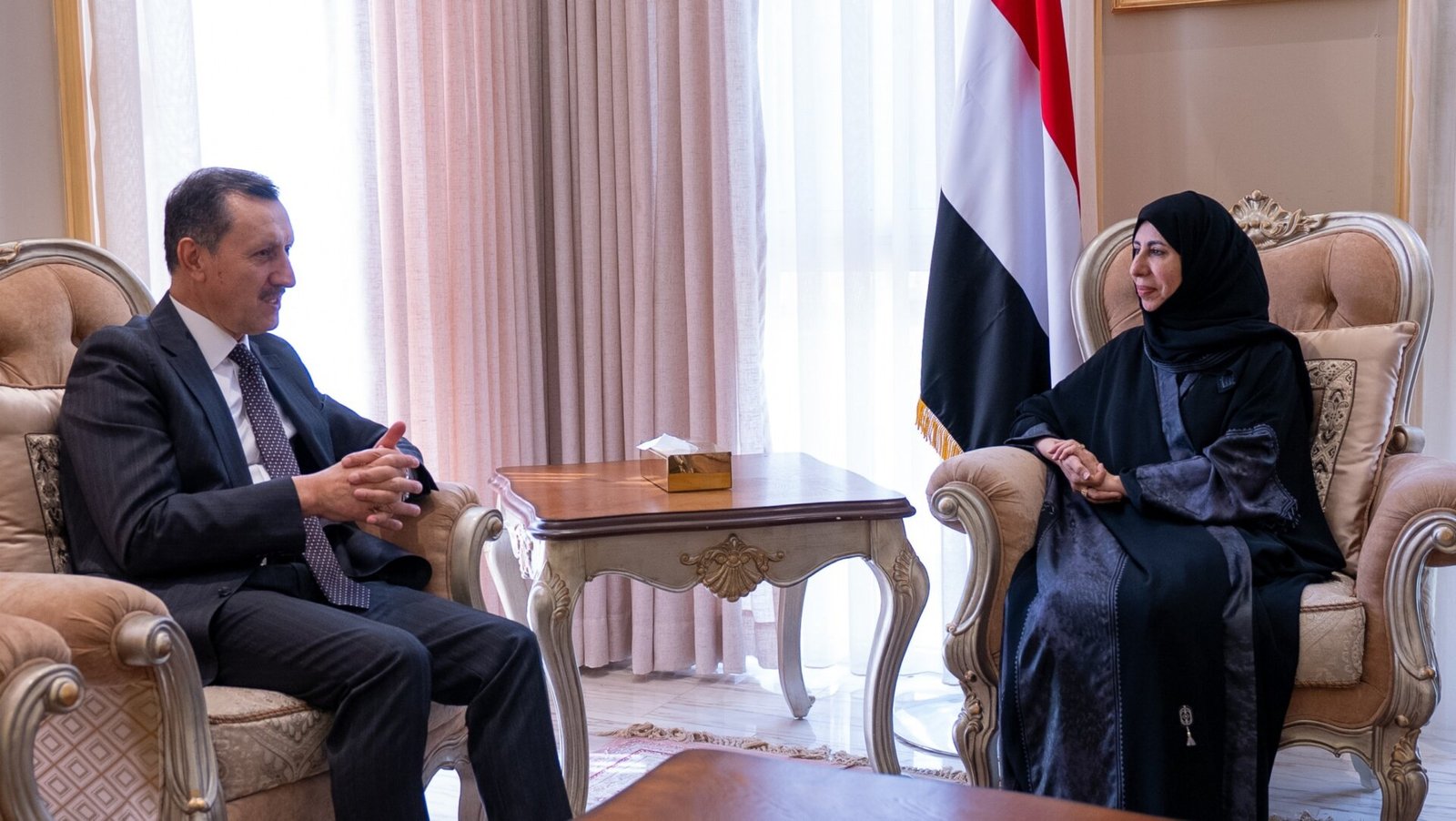Yemeni Foreign Minister Afrah al-Zouba seated with Turkish envoy Emrullah Isler beside a Yemeni flag in Riyadh