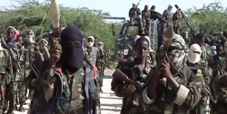 Armed fighters stand in open ground, illustrating reports of Houthi weapons and drone training reaching al-Shabaab in Somalia.