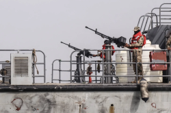 A Yemeni naval patrol boat with a mounted machine gun and crew on deck at a Red Sea port