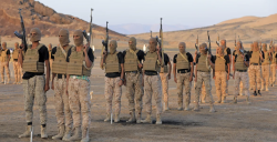 Armed fighters stand in formation in a desert area of Yemen