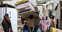Displaced Yemeni families with bedding and belongings at a makeshift shelter site