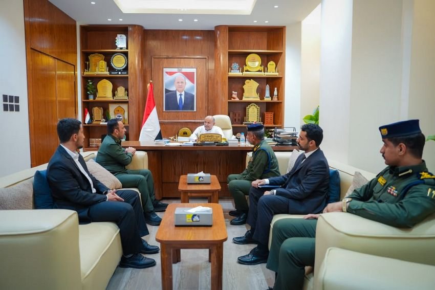 Hadramout governor Salem al-Khanbashi meets officials of Yemen's Immigration, Passports and Nationality Authority in Mukalla, with a Yemeni flag behind them.
