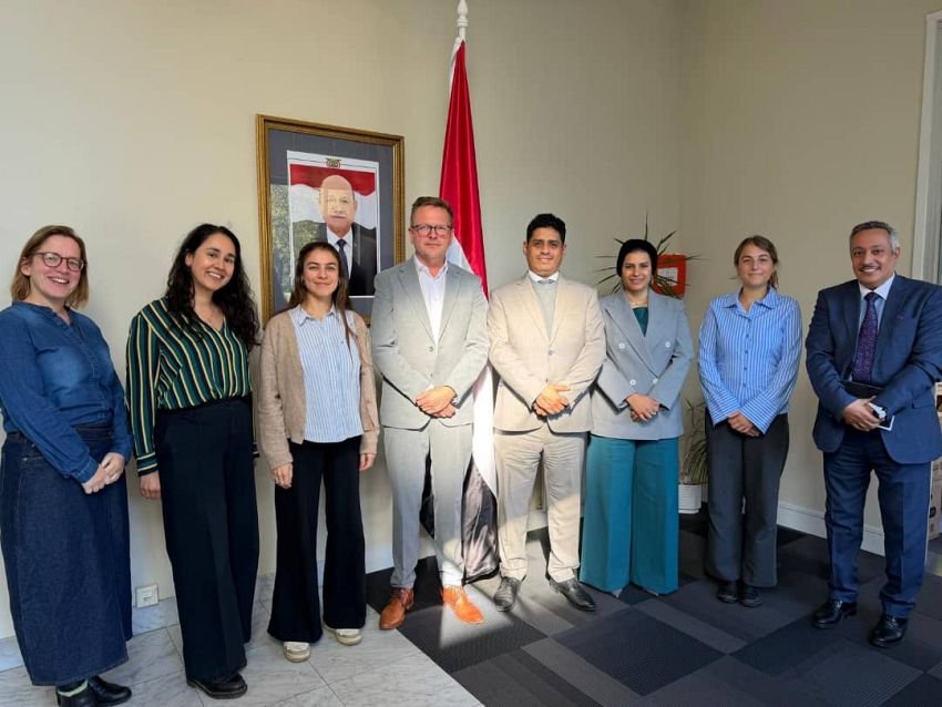 Yemeni and Dutch delegates standing together for a group photograph in a meeting room with a Yemeni flag