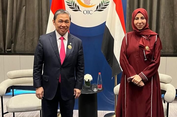 Yemeni Foreign Minister Afrah al-Zouba stands with Indonesian Deputy Foreign Minister Muhammad Anis before an OIC backdrop in Baghdad