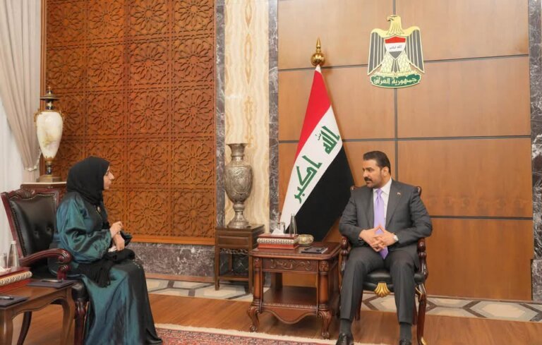 Yemeni Foreign Minister Afrah al-Zouba seated with the Iraqi prime minister beside an Iraqi flag in Baghdad