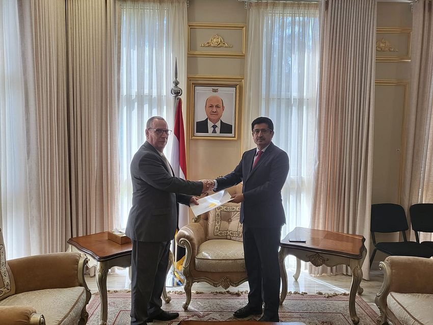 Two diplomats shake hands as a document is handed over in a Yemeni foreign ministry reception room in Aden.