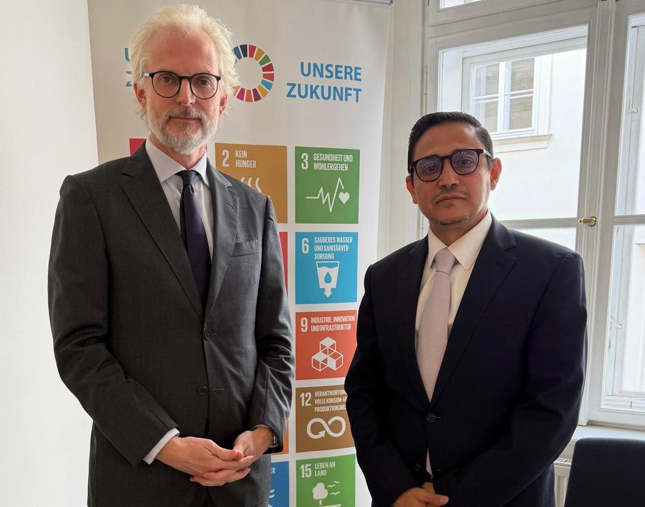 Yemen's ambassador to Austria stands with an Austrian foreign ministry official in front of a UN sustainable development goals display in Vienna