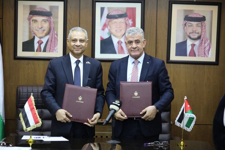 Yemeni and Jordanian officials hold signed folders beside the two national flags after signing a cultural and heritage memorandum in Amman