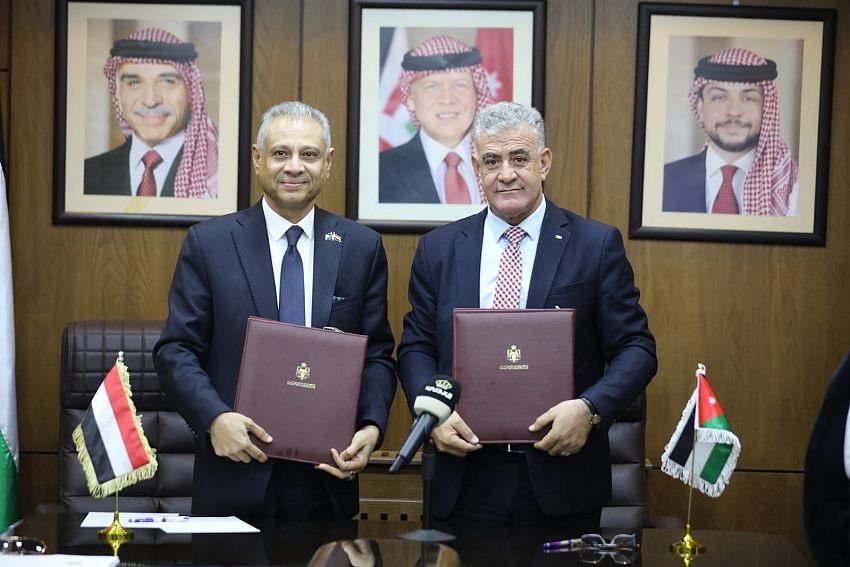 Yemeni and Jordanian officials hold signed folders beside the two national flags after signing a cultural and heritage memorandum in Amman