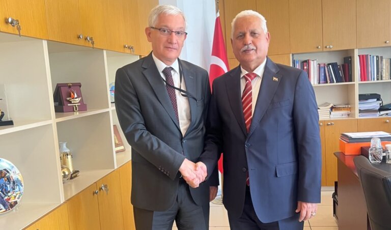 Yemen's ambassador to Türkiye stands with a Turkish foreign ministry official beside a Turkish flag in an office in Ankara