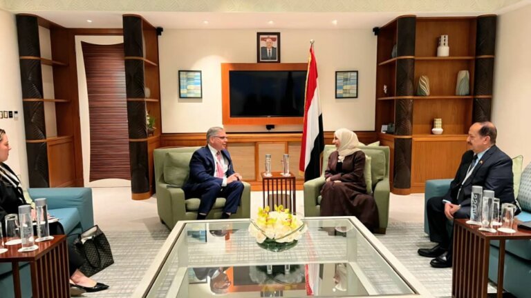 Yemeni Foreign Minister Afrah al-Zouba seated in a bilateral meeting beside the Yemeni flag