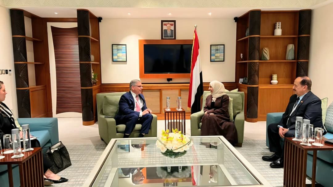 Yemeni Foreign Minister Afrah al-Zouba seated in a bilateral meeting beside the Yemeni flag