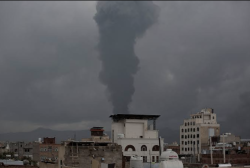 A column of black smoke rises over the skyline of Yemen’s capital Sanaa after airstrikes