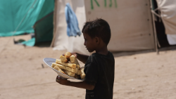 A child carries food through a settlement in Yemen as aid agencies warn of worsening hunger