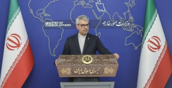 Iranian foreign ministry spokesman Esmaeil Baghaei speaks at a news conference in Tehran, flanked by Iranian flags.