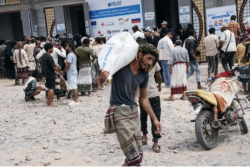 Men carry sacks of food aid from a truck in a street in Yemen