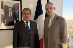 Two diplomats stand together beside a French flag after talks on Yemen at the United Nations in New York