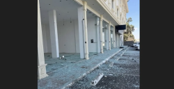 Shattered glass covers the pavement outside a damaged building after missile debris fell